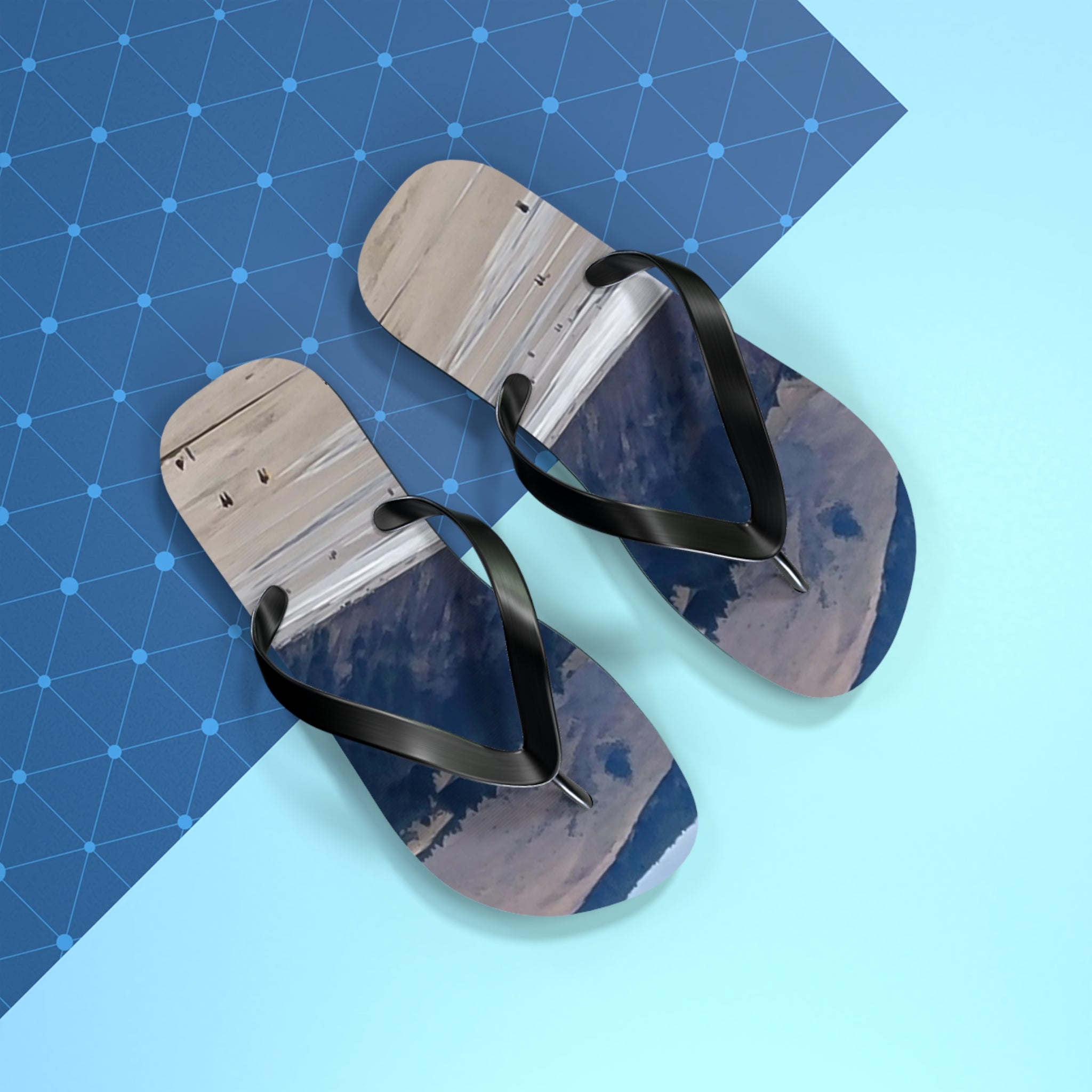 Flip-flops with a beach scene on the soles, placed on a blue geometric background.