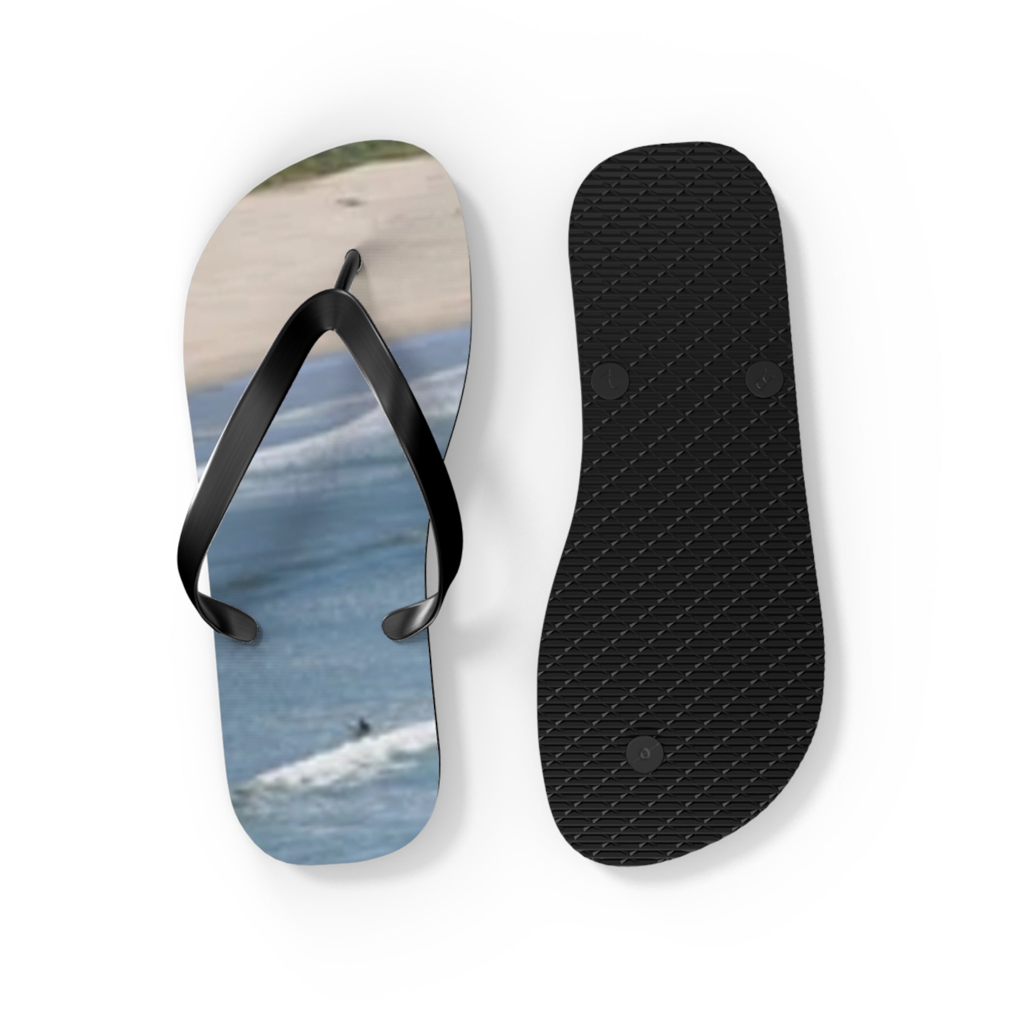 Black and white flip-flops with a beach scene on one sole.
