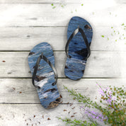 Flip-flops with ocean wave design on a wooden surface.