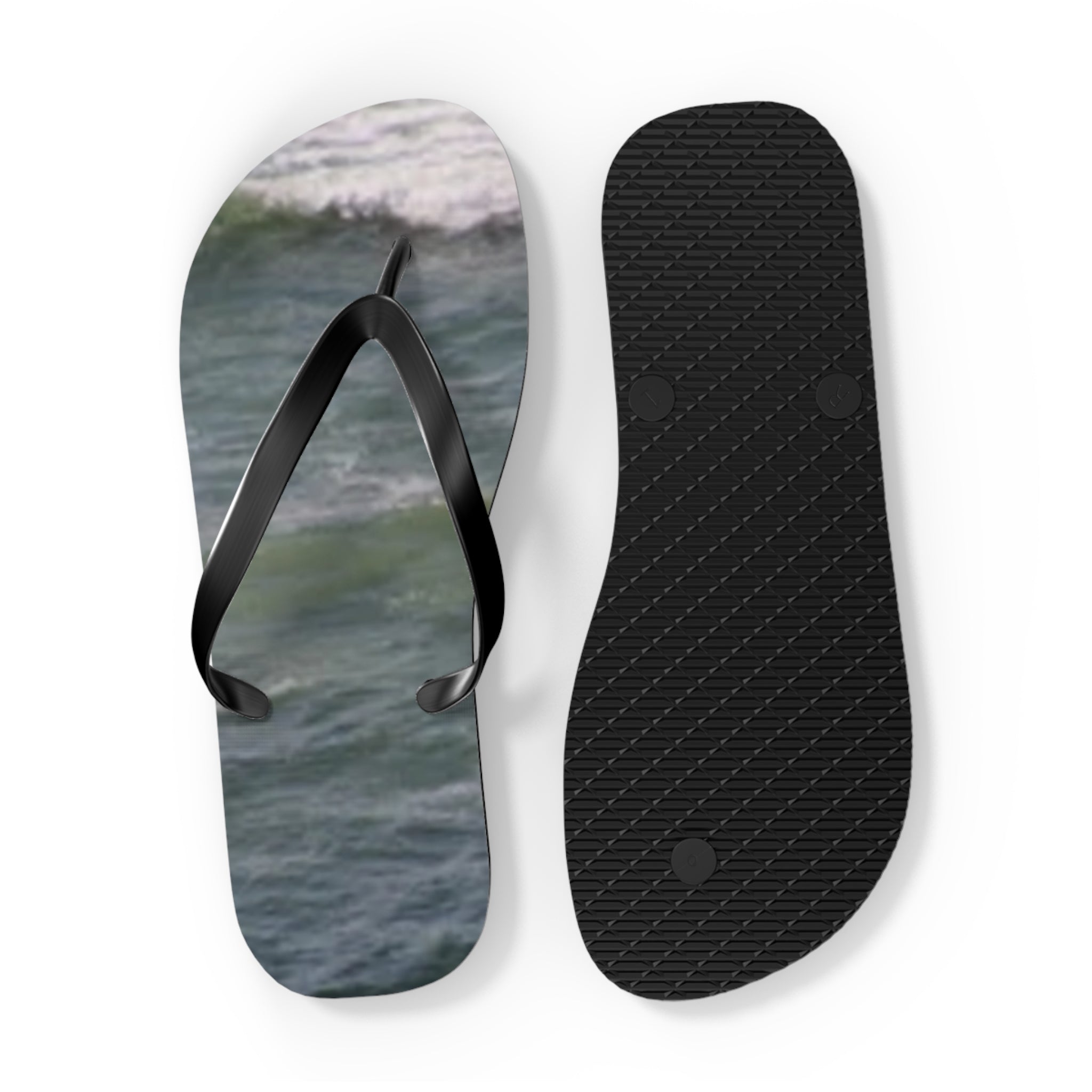 Black flip-flops with a wavy ocean graphic on one sole and textured sole on the other.