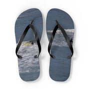 Flip-flops with surfers in the ocean on the soles.