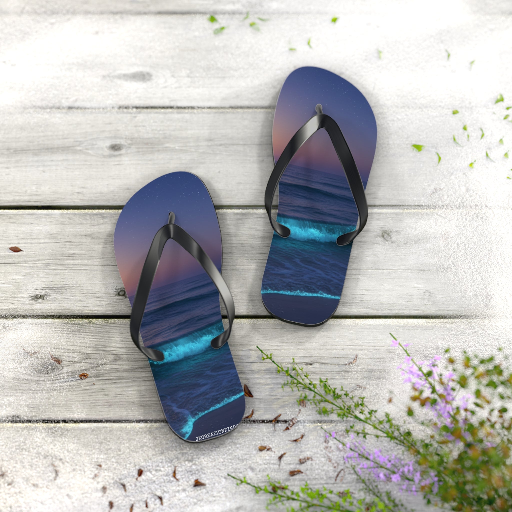 Blue flip-flops with ocean waves and sunset art on wooden planks.