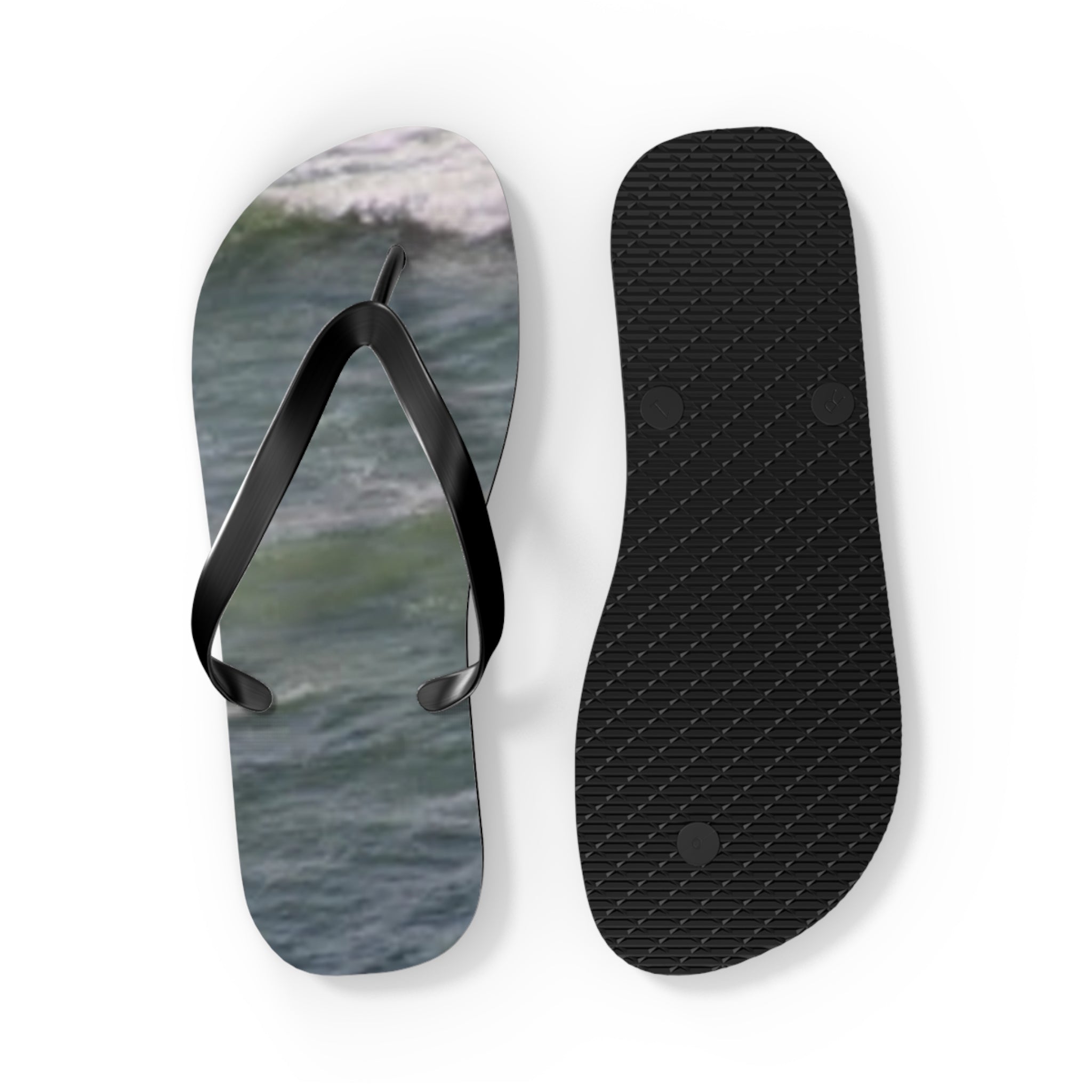 Black flip-flops with ocean waves on the soles, isolated on white.