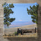 Stone and metal water feature with distant mountain under blue sky.