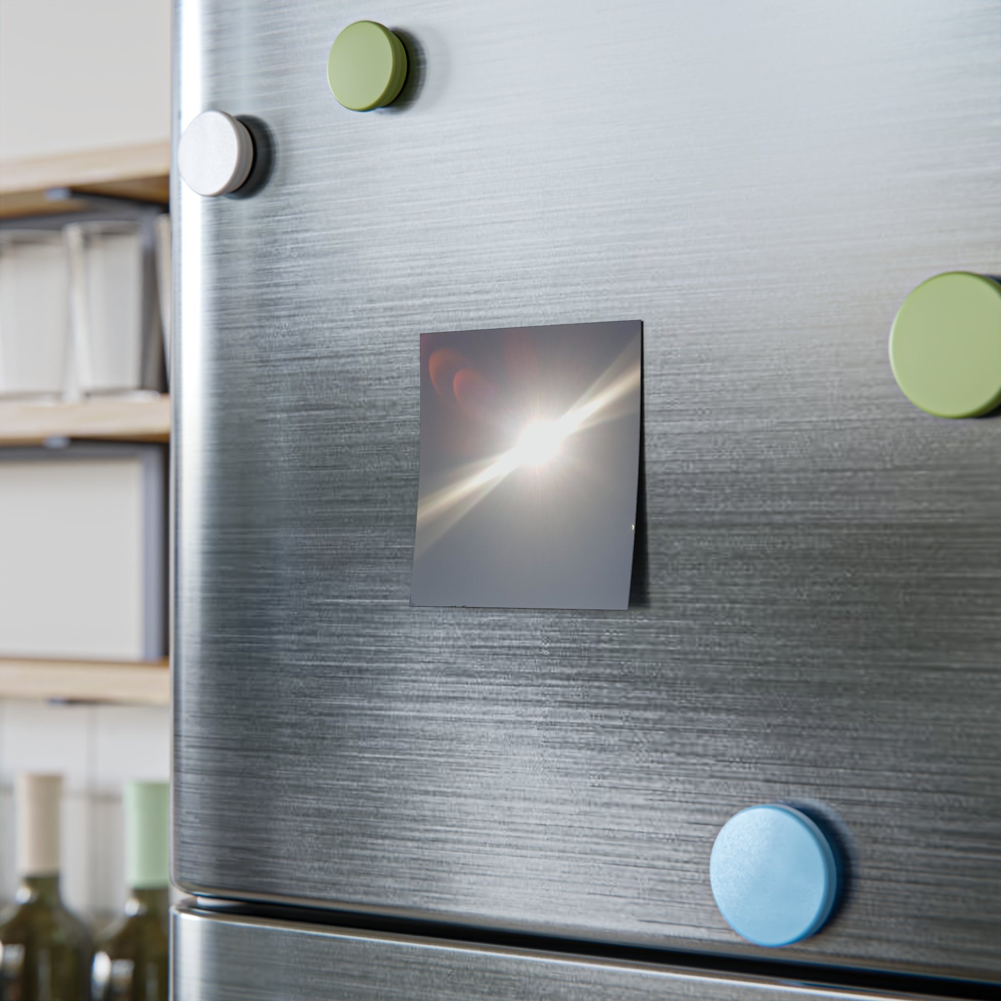 Square magnet with image of a solar eclipse on a refrigerator door.