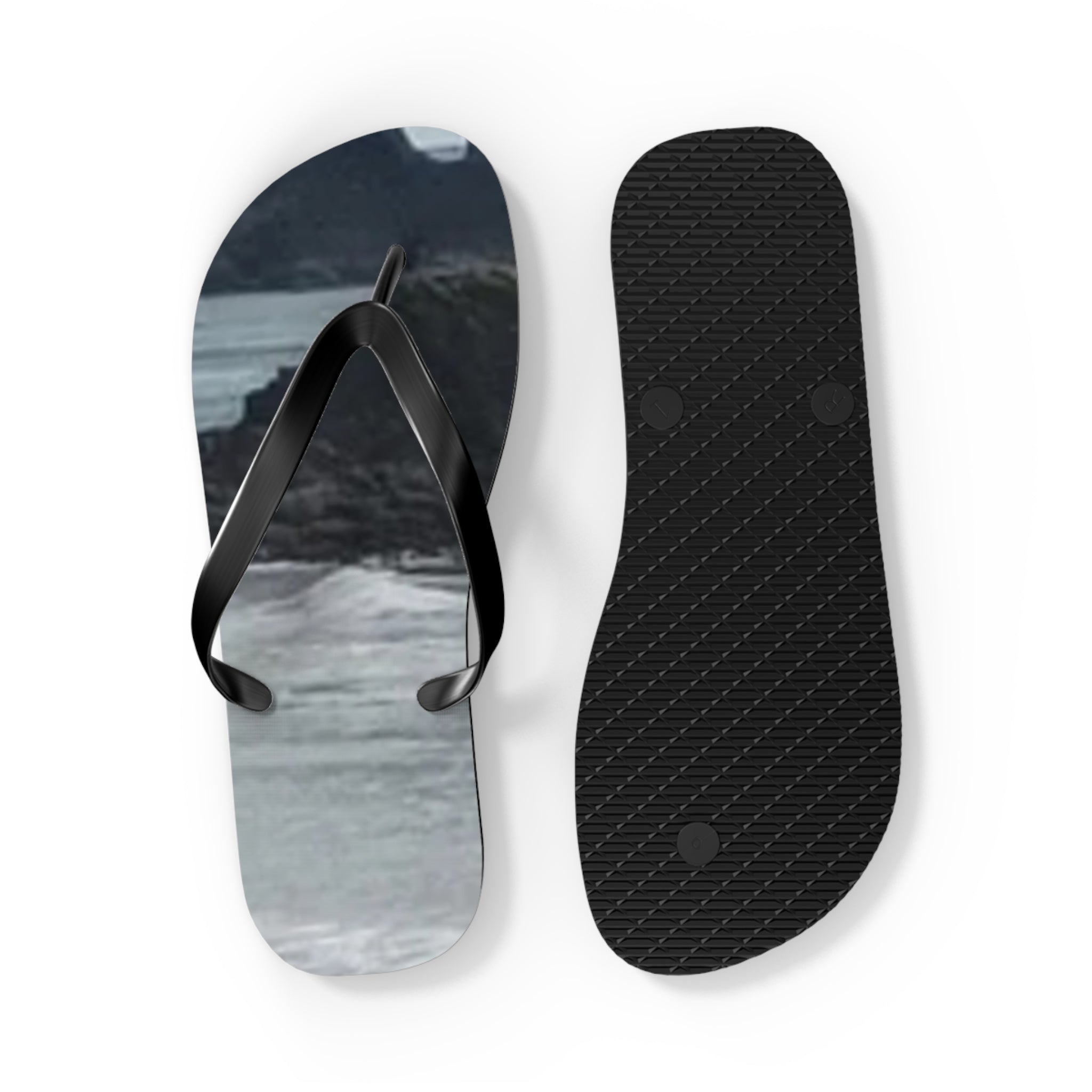 Black flip-flops with a scenic water and mountain landscape on one sole.
