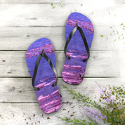 Purple flip-flops with a rocky shore design on a weathered wooden surface.