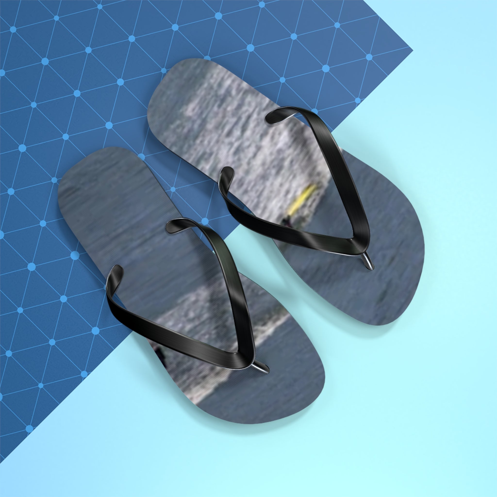 Gray flip-flops with black straps on a blue and white background.