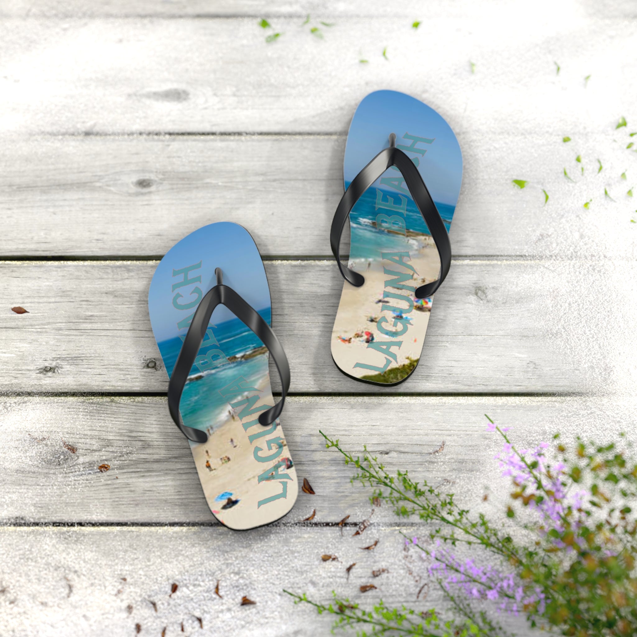 Flip-flops with "Laguna Beach" text and beach scene on weathered wood.