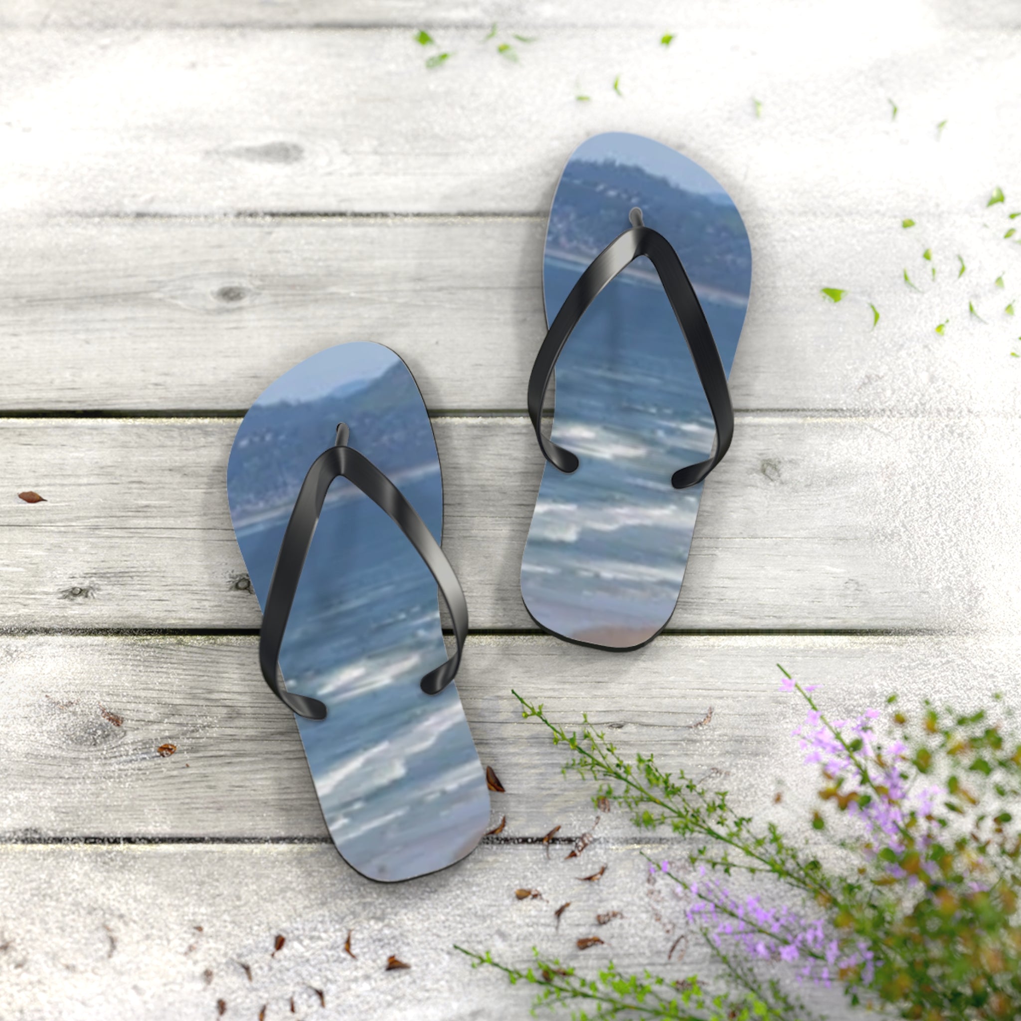 Flip-flops with a beach and ocean scene on a wooden surface.