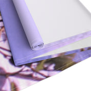 Rolled lavender fabric with blurred floral background.