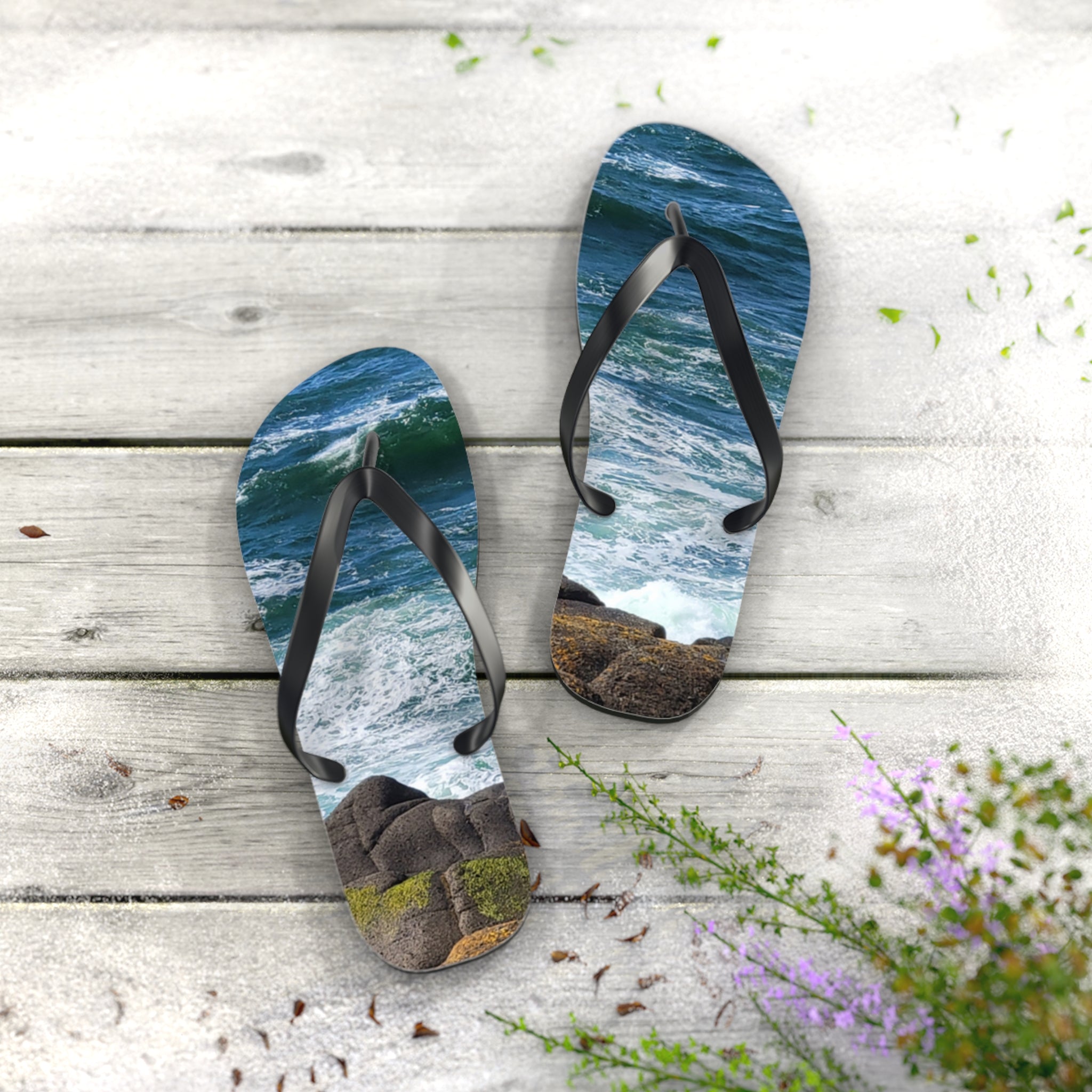 Flip-flops with ocean wave and rocky shore design on white wooden planks.