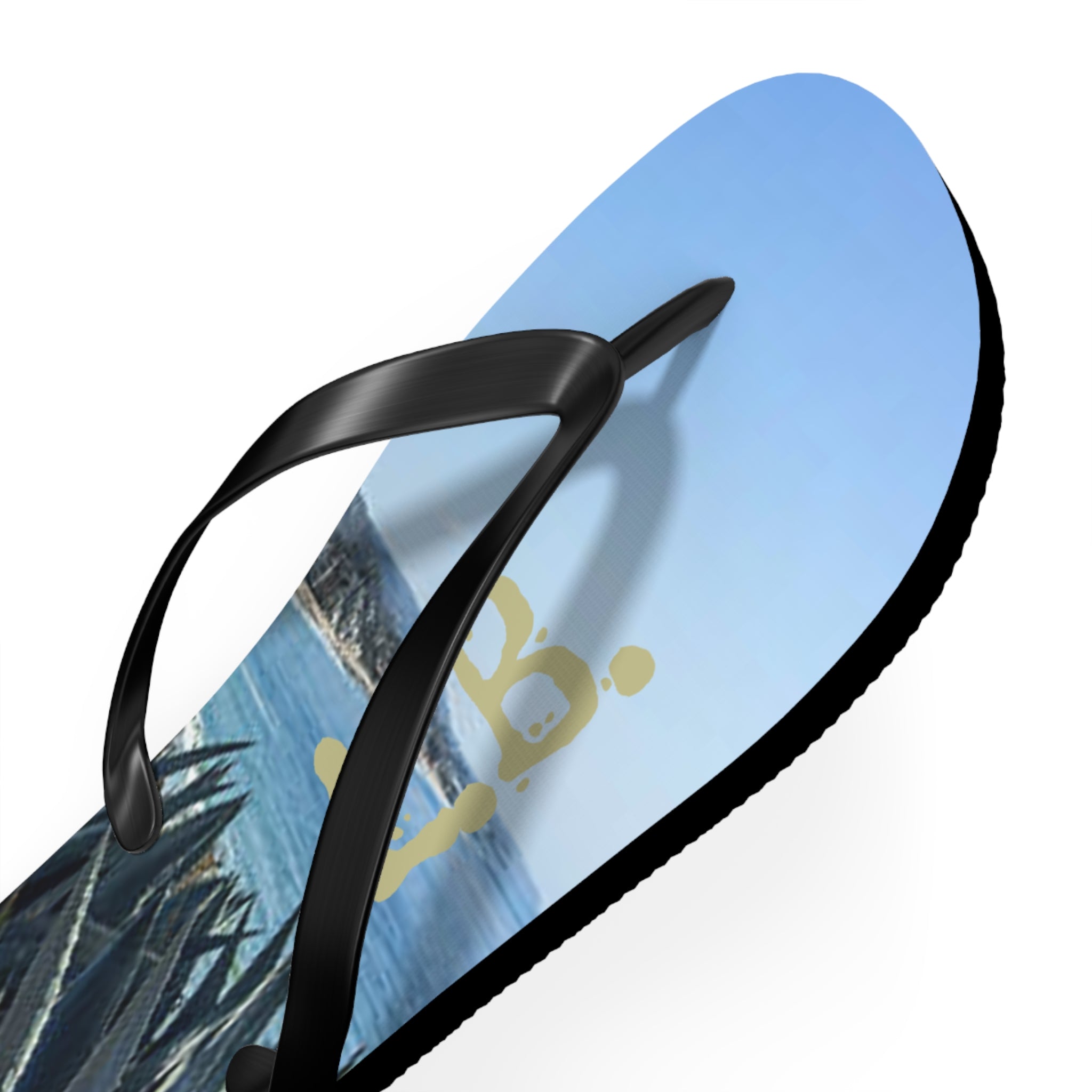 Black flip-flop with beach scene and gold logo on the sole.