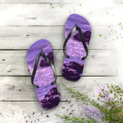 Purple flip-flops with rocky beach scene on wooden planks.
