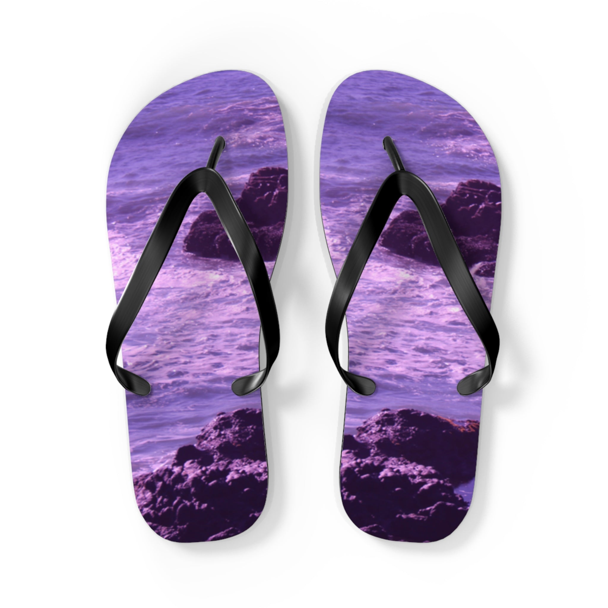 Purple flip-flops with a rocky ocean wave design on a white background.