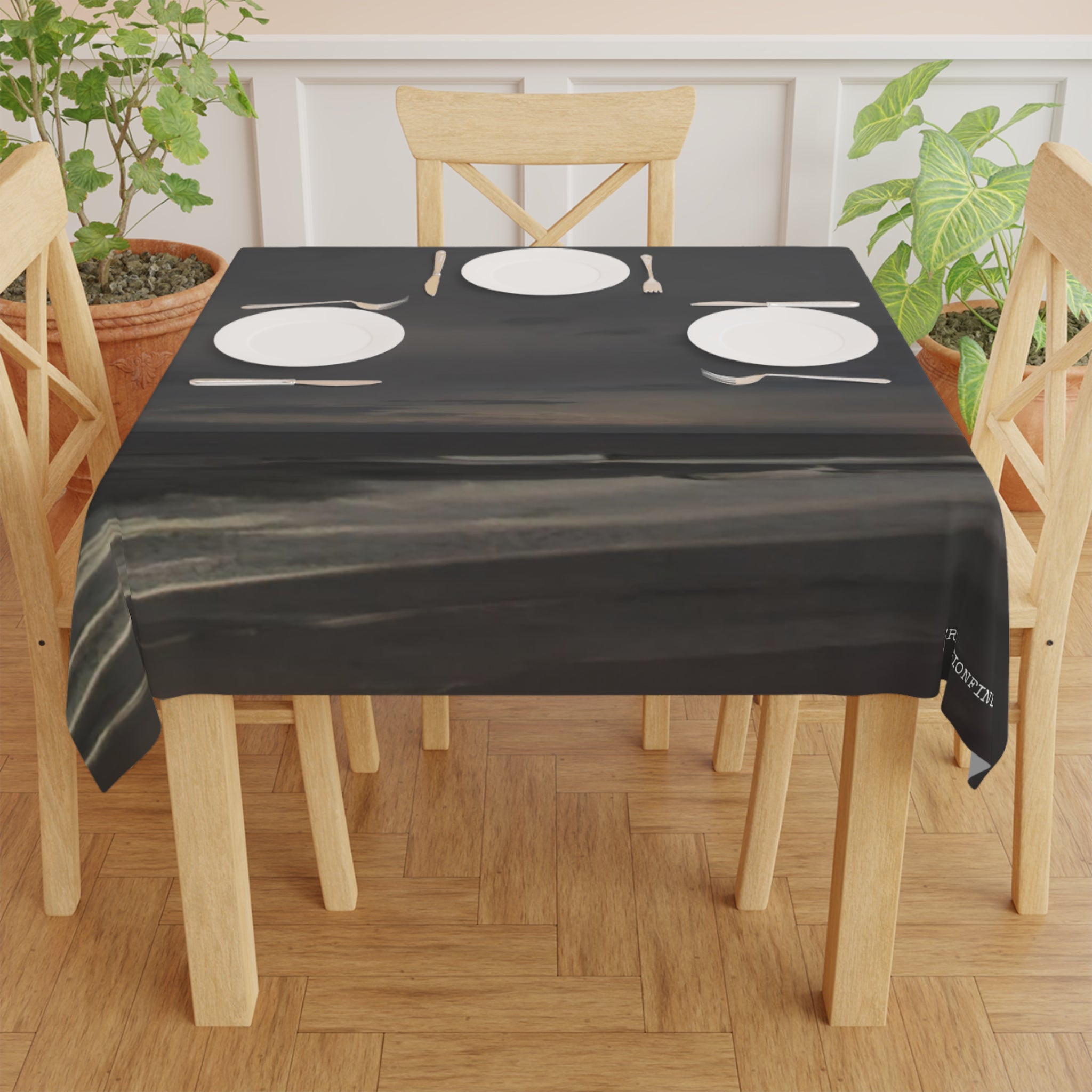 Dark tablecloth with abstract white text, set on a table with plates.