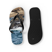 Black flip-flops with a scenic ocean wave and rocky shore print on the right sandal.