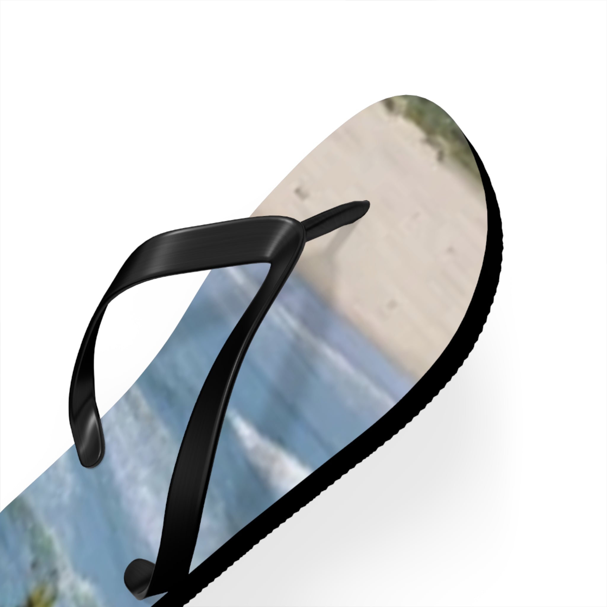 Black flip-flop with a beach and ocean scene printed on the sole.