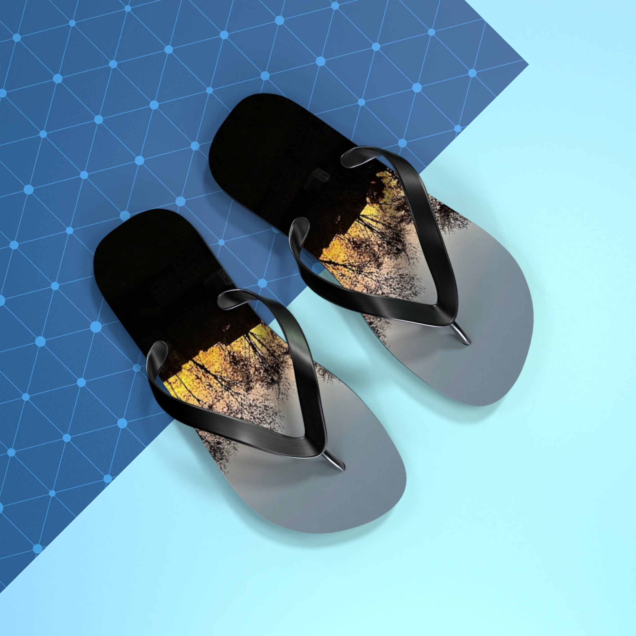 Black flip-flops with a sunset tree reflection on the soles.