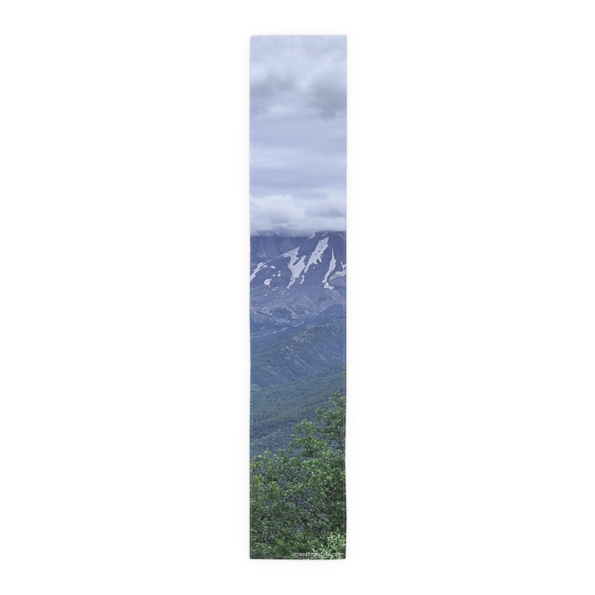 Tall panoramic view of a cloudy mountain range with green forested foothills.