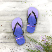 Purple flip-flops with ocean waves printed on straps, resting on wooden planks.