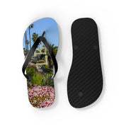 Flip-flops with a beach scene and palm trees on one sole, black sole on other.