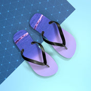 Purple flip-flops with a sunset ocean view on each sole, on a blue background.