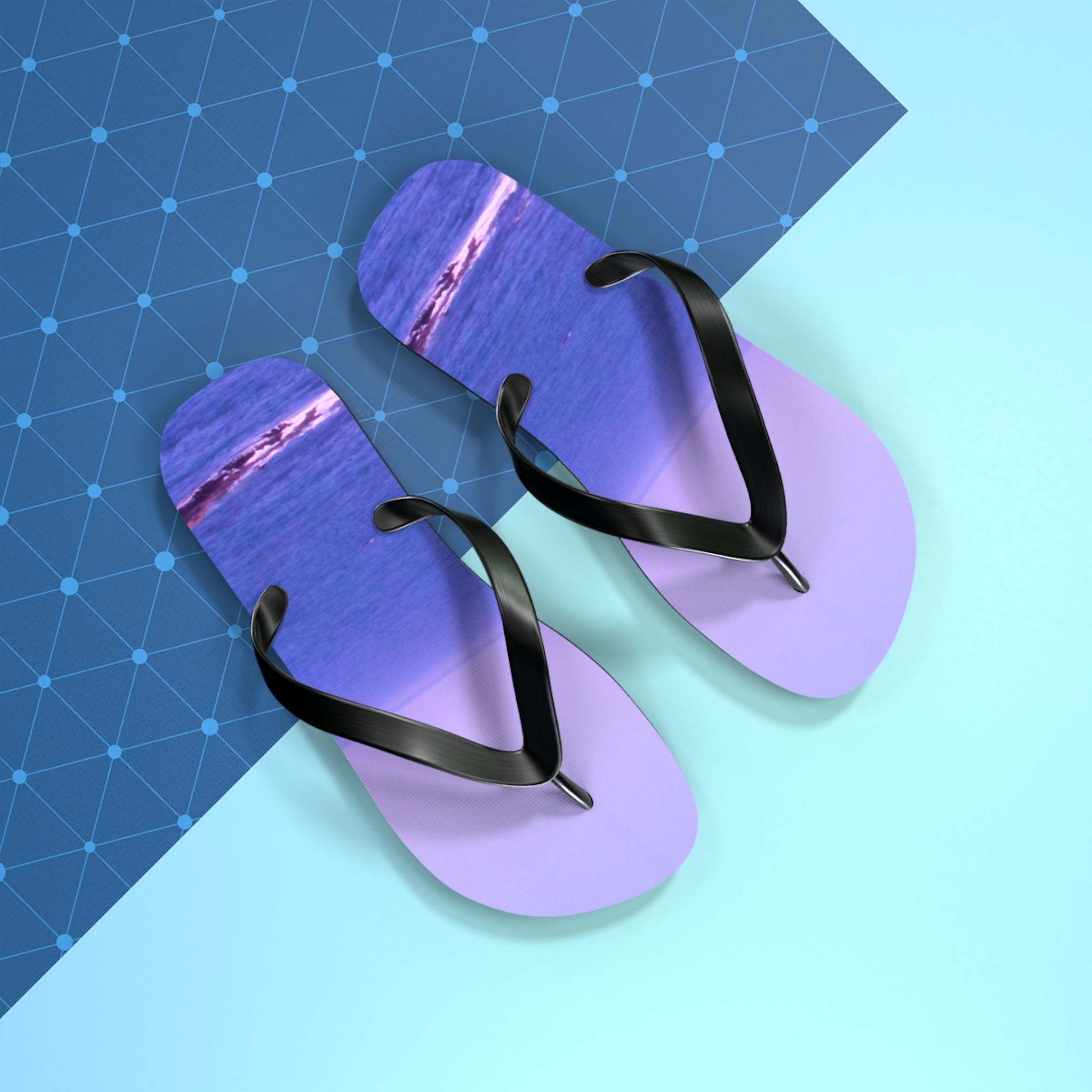 Purple flip-flops with a sunset ocean view on each sole, on a blue background.