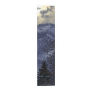 Runner with a winter forest and mountain landscape under a cloudy sky.