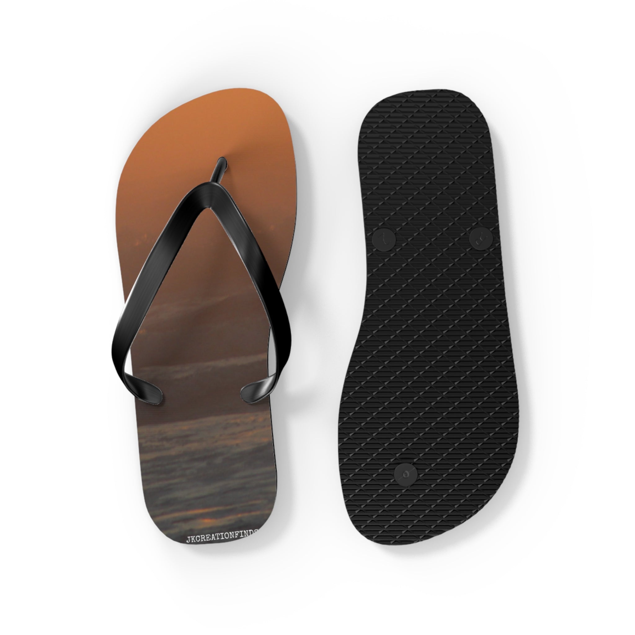 Flip-flops with a sunset beach scene and textured black sole.