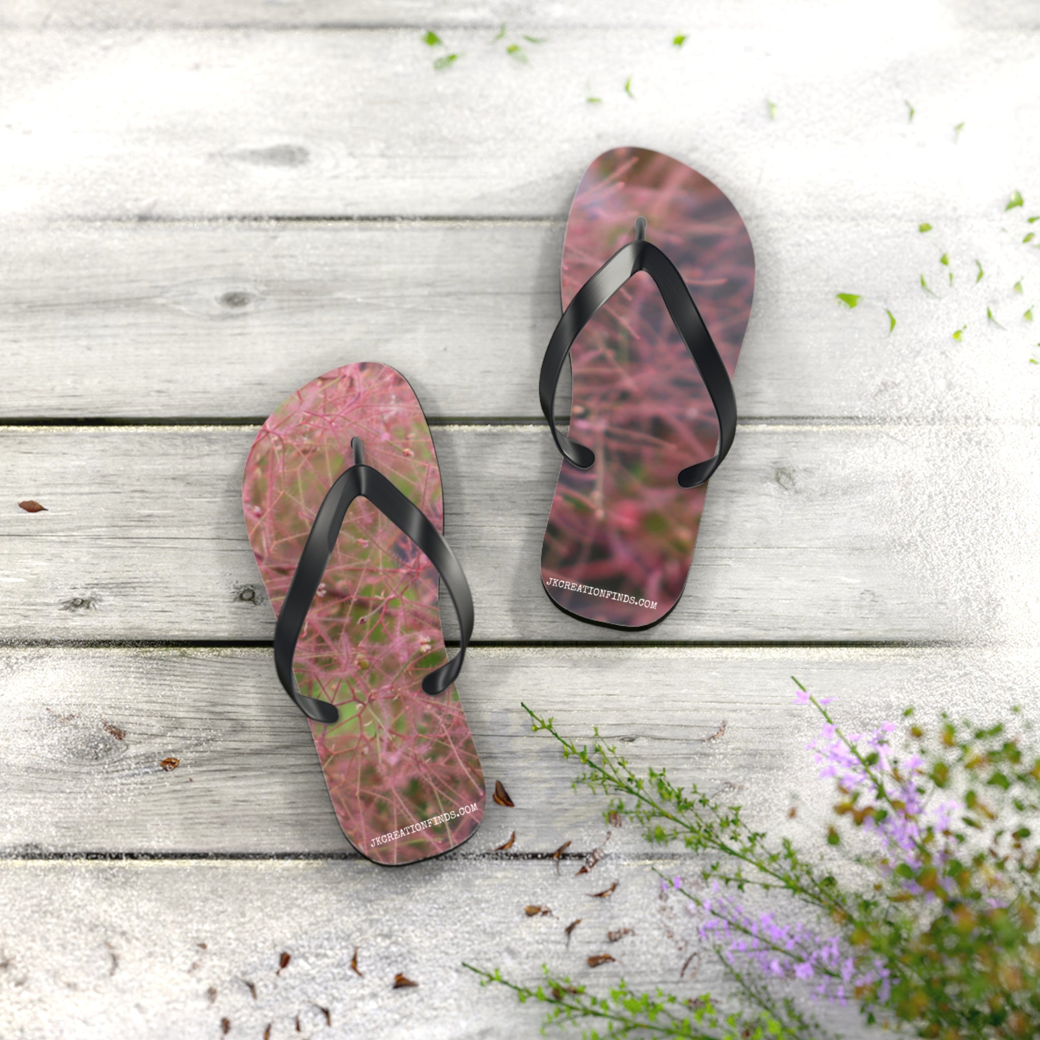 Flip-flops with pink and green floral pattern on white wooden planks.