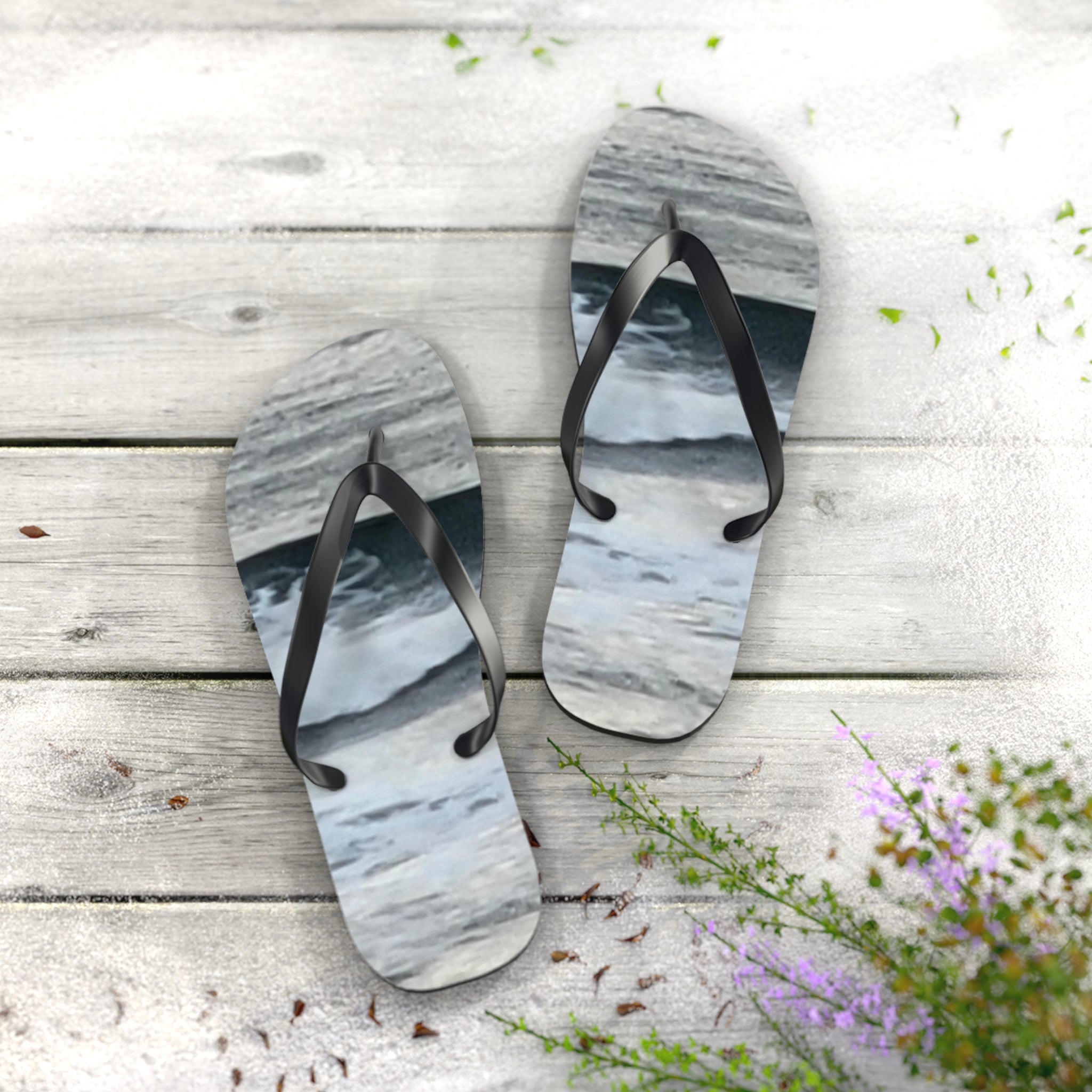 Flip flops with abstract ocean waves design on wooden surface.