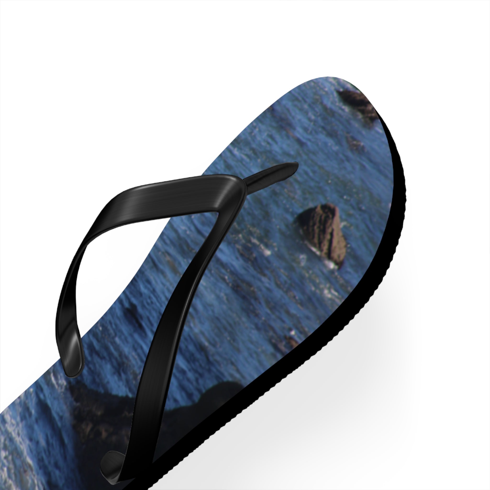 Flip-flop with ocean wave pattern and black straps on white background.